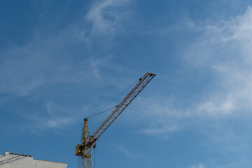 Construction crane towering against a clear blue sky during the day in an urban setting