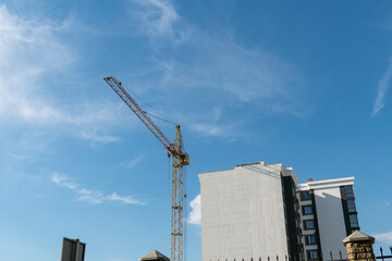 Construction crane stands tall against blue sky near urban building site during daylight hours