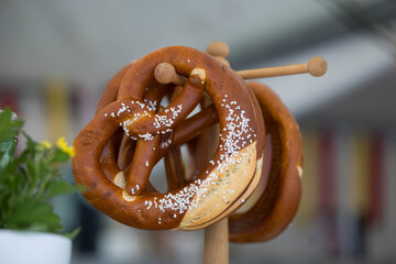 Fresh salted pretzels hanging on display stand with blurred background