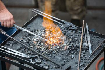 Hands at forge: blacksmith twisting hot iron on coal-fired anvil