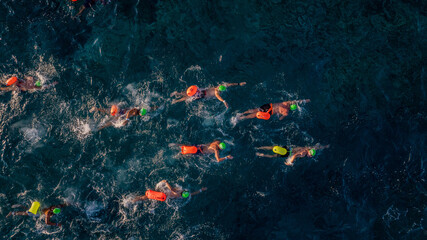 Nadadores en mar cristalino rodeando boya naranja durante competencia de aguas abiertas.