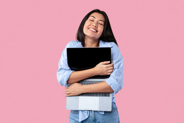 Technology Lover Concept. Happy asian woman hugging laptop with black blank empty screen, holding...