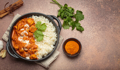 Aromatic Indian chicken tikka masala served with rice and coriander, turmeric, garlic, cinnamon sticks, traditional dish of India top view, copy space