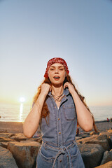 lifestyle woman in modern boho-western denim street style posing outdoors at sunset with warm film...