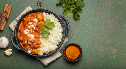 Aromatic Indian chicken tikka masala served with rice and coriander, turmeric, garlic, cinnamon sticks, traditional dish of India top view, copy space