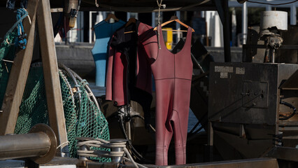 Hanging wetsuits and fishing nets on industrial boat deck