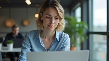 Focused business woman working on a laptop in a professional office setting
