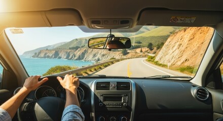 A man driving a car with a view of a scenic coastal road and ocean, first-person perspective. Summer road trip concept.