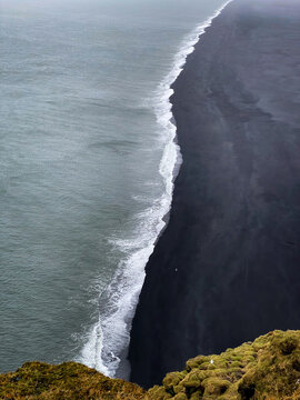 Scenic view from the cliffs above Dyrh&oacute;laey Beach, Iceland, with dramatic black sand shoreline