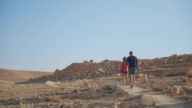 Active senior couple walking and hiking in desert hill on sunny day outdoors. Elderly woman and man enjoying a day hike in open arid dry desert track or footpath in hot weather. Sport hobby activity