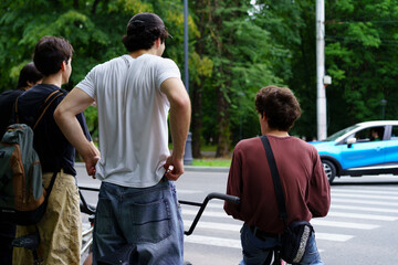 Group of young people waiting at a crosswalk with bicycles in a city park during daytime