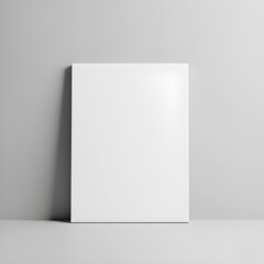 A blank white canvas stands against a light gray wall, casting a subtle shadow on a smooth surface below.