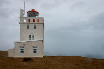 Scenic view of Dyrhólaey Lighthouse on the southern coast of Iceland, standing on a cliff above...