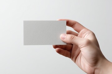 Obraz premium Index card held by hand against a white background showcasing a simple, minimalistic setup ideal for note-taking or creative tasks