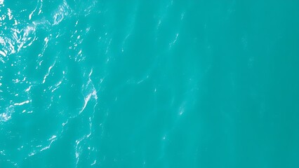 Aerial view of turquoise ocean waves forming abstract patterns, embodying a minimalist summer seascape.