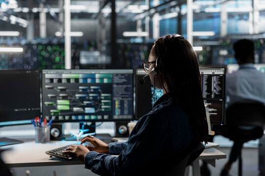 IT expert in data center wearing audio headset providing technical support to customers, troubleshooting errors. Server farm employee doing operational technical interventions requested by clients