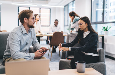 Two professionals engaged in deep discussion on business topics, emphasizing strategy, leadership, and mobile productivity in a modern shared workspace, with coffee and digital tools present