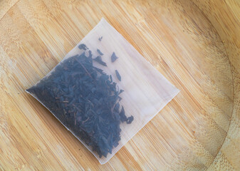 Natural Tea Bag with Loose Leaf Blend on Wooden Surface