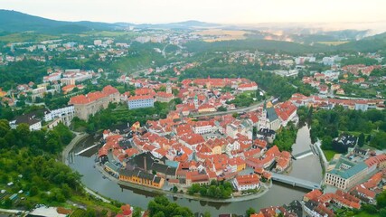 Experience a breathtaking morning view of Cesky Krumlov from above, showcasing its UNESCO heritage, winding river, and distinct architecture framed by lush greenery.
