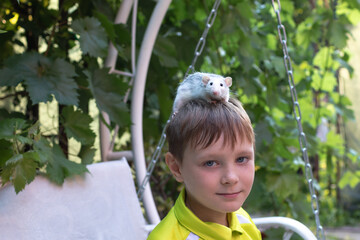 Boy put a  pet rat on his head while out for a walk