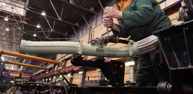 Assembly of military equipment in a wheel tractor plant with skilled workers engaged in precision tasks