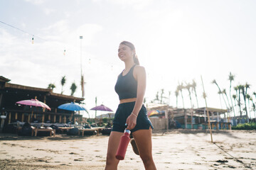 Woman in orange sportswear performs yoga pose on sandy beach, illustrating harmony between physical...