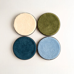 Four textured round pads in cream, olive green, dark teal, and light blue, arranged on a crisp white background. Ideal for textile, home decor, and craft themes.