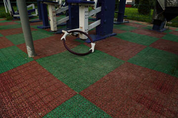 Gym equipment objects in outdoor urban street sport ground with safe rubber surface green red colors. Dumbbell, pilates ring, yoga block, fitness band lying on the floor with no people