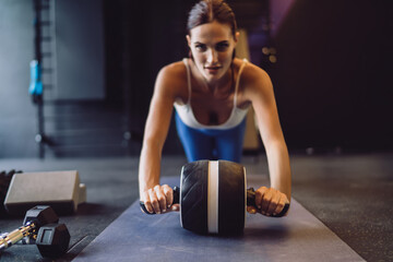 Close-up view of determined woman using ab roller, emphasizing core tension and technological precision within structured strength-building routines.