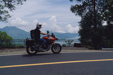 Motorcyclist uses smartphone navigation app while riding through dense forest, showcasing integration of mobile technology in modern solo travel experiences.