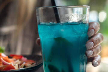 Blue cocktail in the hands of a girl