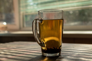 A glass of tea standing on a table by the window