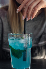A young woman enjoys a cocktail in a restaurant.