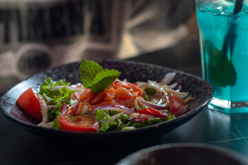 Salad with red fish and blue cocktail