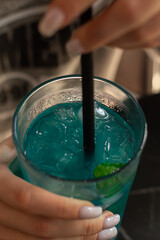 A young woman enjoys a cocktail in a restaurant.