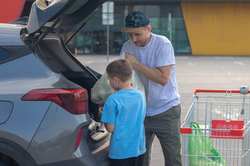 A young man and his son load shopping into a car