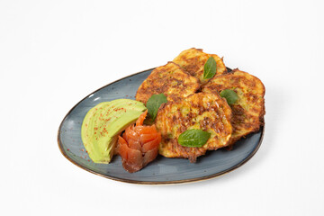Omelette zucchini fritters on a plate with avocado and red fish on a white background