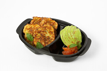 Omelette zucchini fritters on a plate with avocado and red fish on a white background