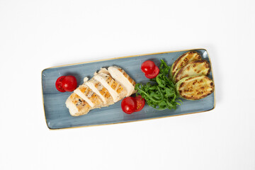 Grilled chicken fillet with grilled vegetables on a plate on a white background