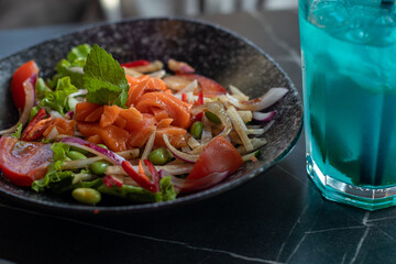Salad with red fish and blue cocktail