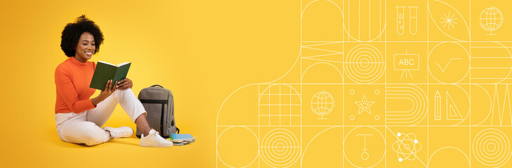 A student sits on the floor, deeply focused on reading a book. Surrounded by educational materials, the bright painted background enhances the vibrant study atmosphere.