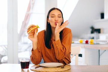 Satisfied woman eating tasty burger, having cheat meal for lunch, ordering takeaway fast food and enjoying tasty unhealthy snack