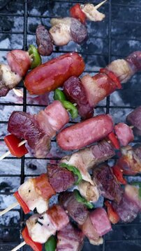 Chilean Independence Day vertical video: Overhead close-up of grilling anticuchos and longanizas over smoky coals with fire, camera pulls back