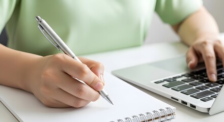 Stylish writer taking notes with modern laptop at bright desk