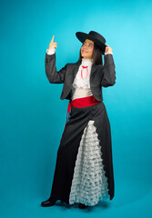 Young latina woman wearing traditional huasa clothing and hat, pointing and looking upwards while...