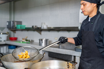 Chef frying fish in a wok in a peruvian restaurant kitchen