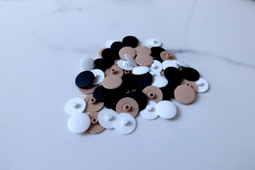 Set of multicolor plastic screw covers in black, white, and beige for furniture assembly and...