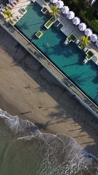 Aerial view of young woman swimming in the pool at the sandy beach.Bali.Indonesia.Vertical video