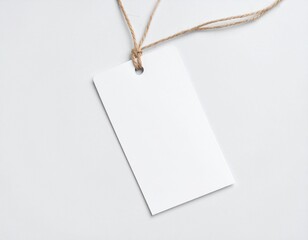 Etiqueta colgante rectangular blanca con hilo natural, sobre fondo blanco suave.
