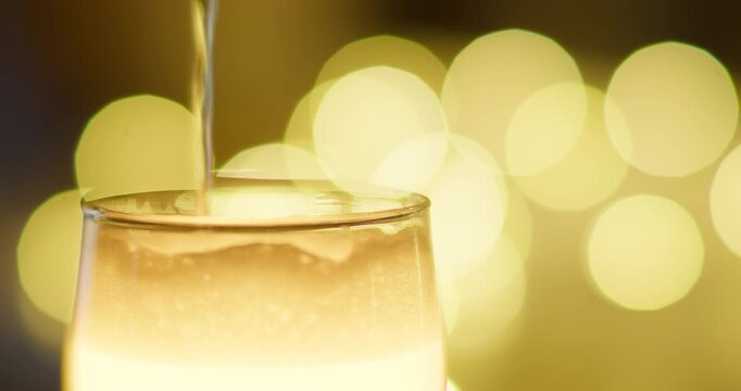 Beer is poured into a glass tumbler on a background of golden sides